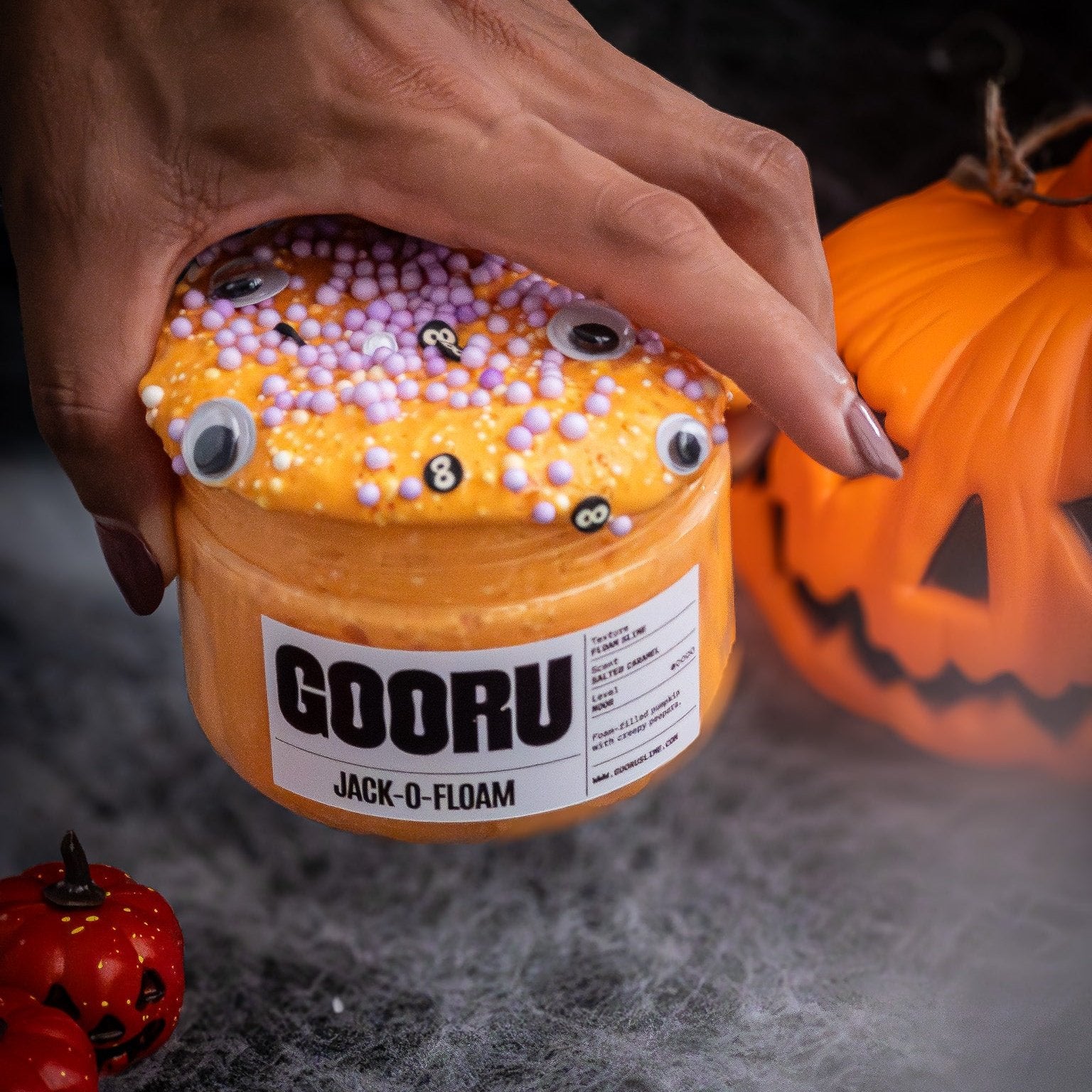 Hand holding vibrant orange foam-filled slime with googly eyes, showcasing its squishy, non-sticky texture and playful Halloween theme. Ideal for sensory play and stress relief.