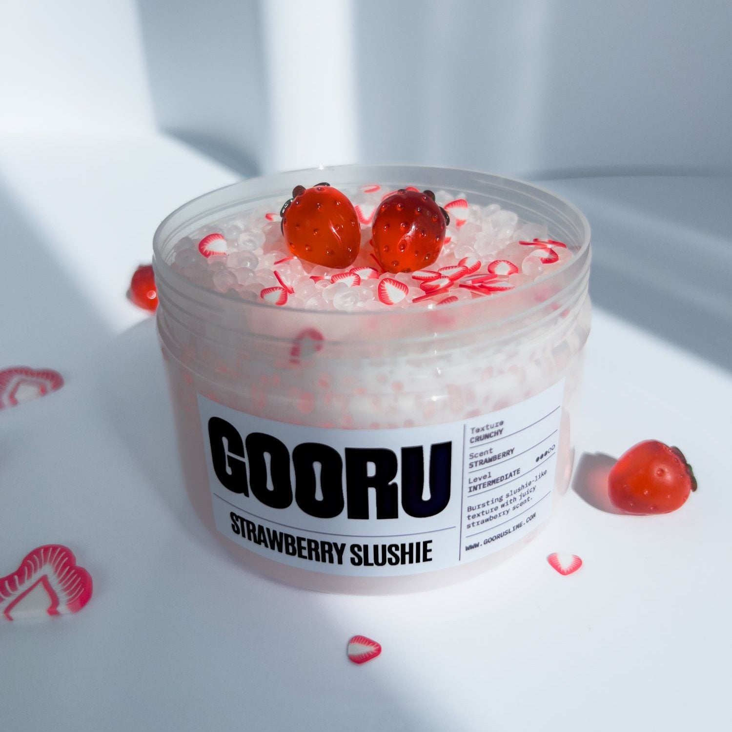 Product shot of Strawberry Slushi Slime, with red strawberry charmes, designed and manufactured  by Gooru Slime, Dubai, UAE