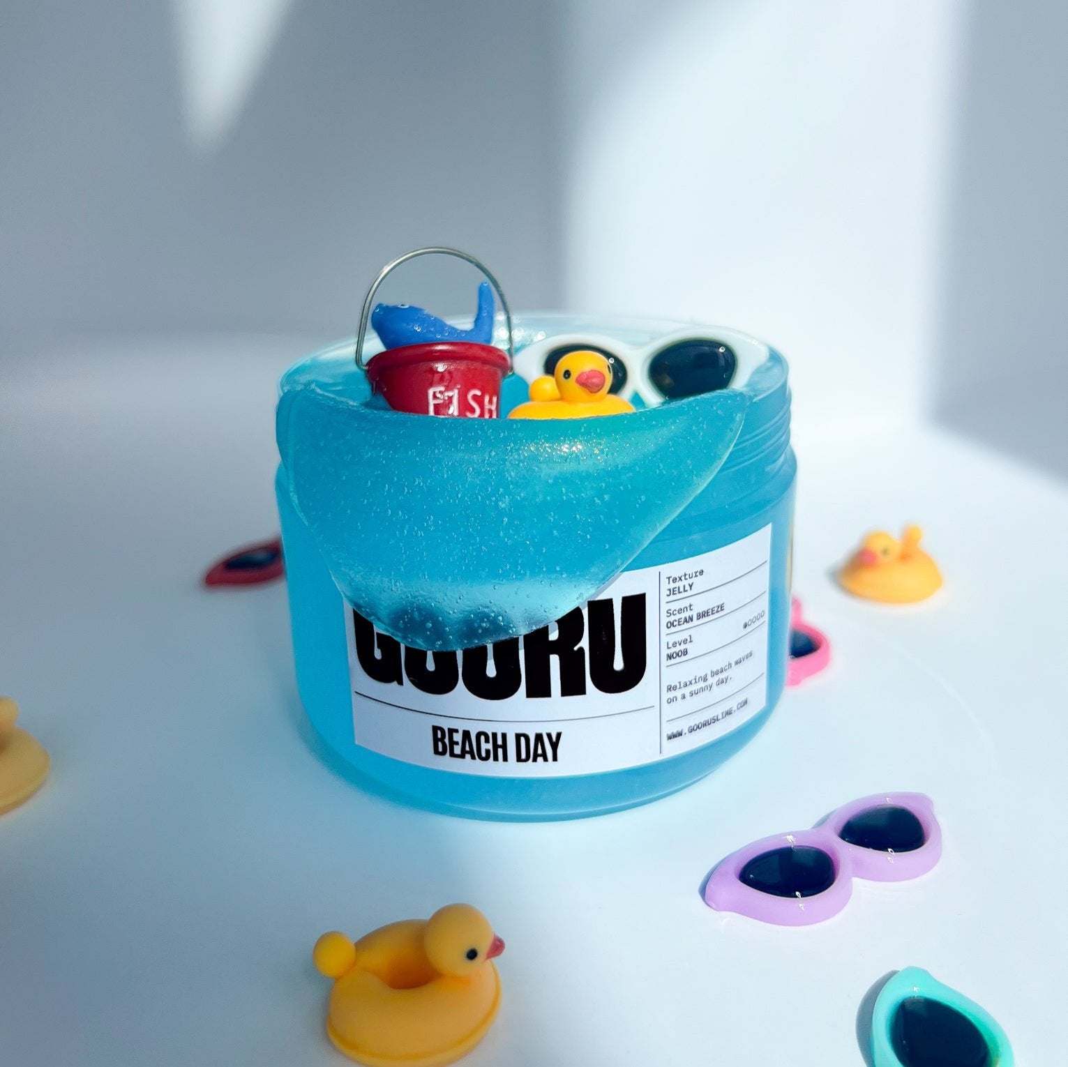 Product shot of Beach day Slime, with beach bucket and sunglasses charms on top, designed and manufactured  by Gooru Slime, Dubai, UAE