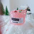 The Snowflake Squad slime jar on display with its pink glittery texture and festive charms, including a polar bear and reindeer figurine. The setup features a snowy winter wonderland with trees and holiday decorations in the background.